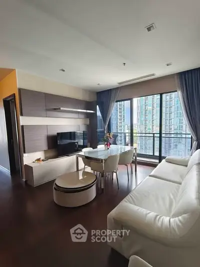Modern living room with large windows and city view, featuring sleek furniture and elegant decor.