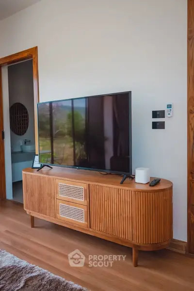 Stylish living room with modern TV stand and large flat-screen TV, showcasing elegant interior design.