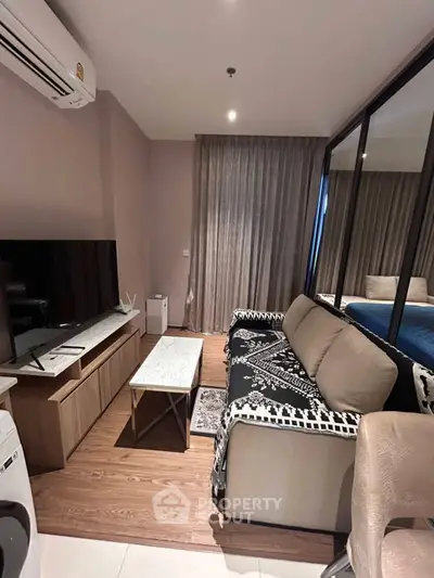 Modern living room with stylish decor, featuring a cozy sofa, TV, and elegant curtains.