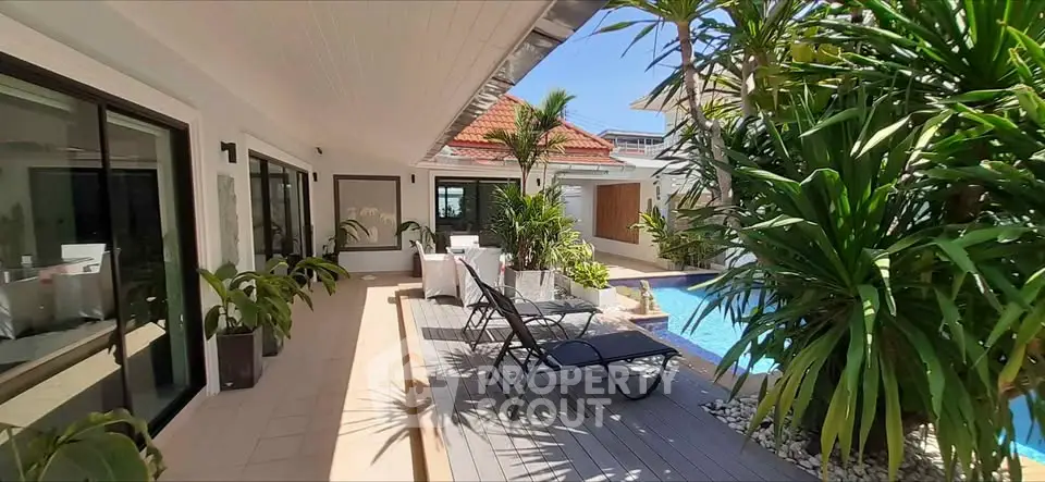Luxurious poolside patio with lush greenery and modern lounge chairs