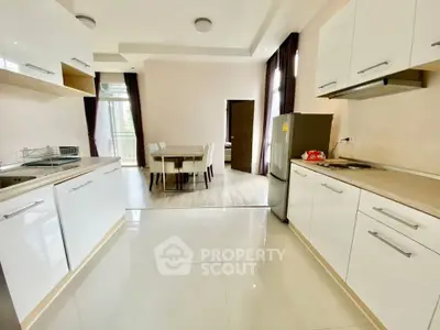 Spacious modern kitchen with sleek white cabinets and dining area, perfect for family gatherings.
