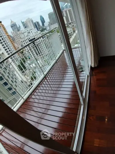 Stunning city view from a sleek balcony with polished wooden flooring.