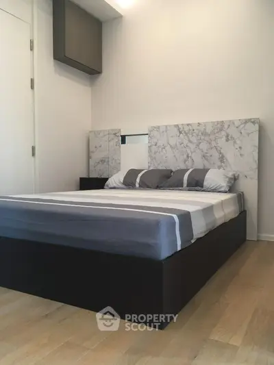 Modern bedroom with stylish marble headboard and sleek wooden flooring.