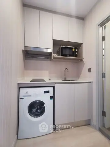 Compact modern kitchen with washing machine and microwave in sleek apartment