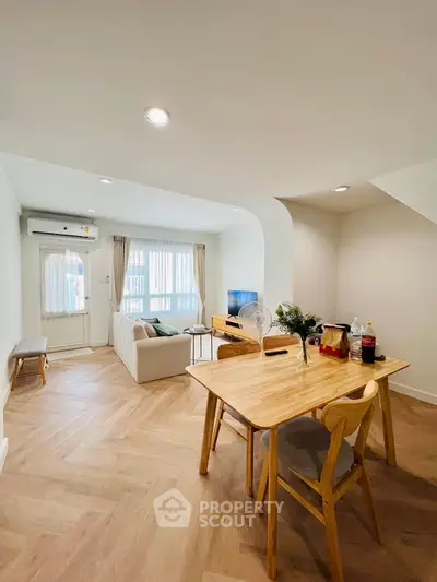 Modern living room with dining area, featuring wooden flooring and stylish furniture.
