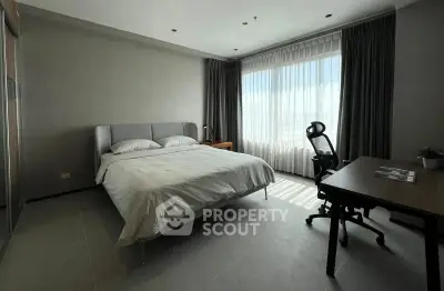 Spacious bedroom with modern decor and large window offering natural light.