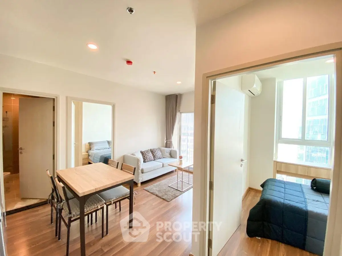 Modern apartment interior with cozy living room and dining area, featuring wooden flooring and ample natural light.
