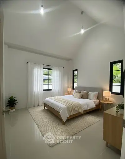 Spacious modern bedroom with high ceiling and natural light