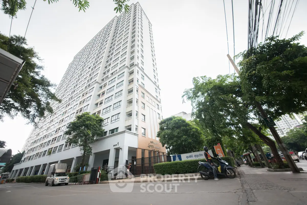 Modern high-rise building with lush greenery and street view, ideal for urban living.