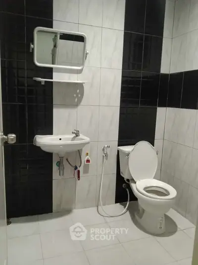 Modern bathroom with sleek black and white tile design and essential fixtures.