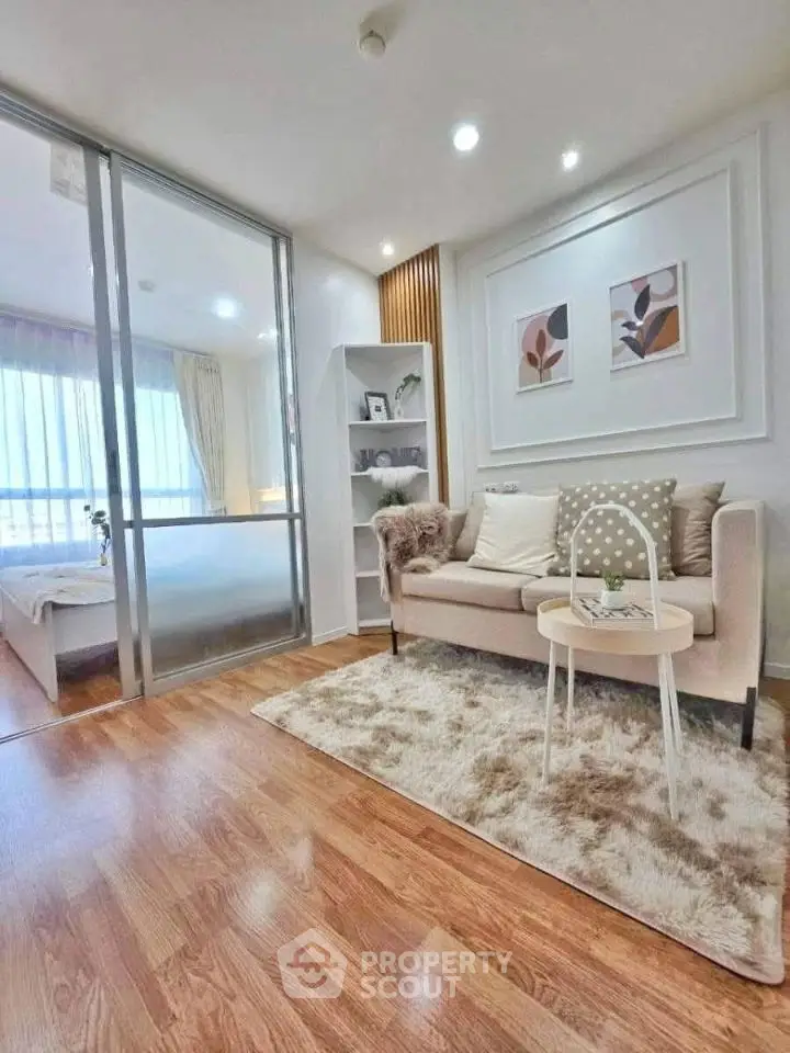 Modern living room with cozy decor and sliding glass doors leading to a bright bedroom.