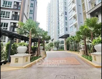 Luxurious modern apartment building entrance with lush greenery and palm trees.