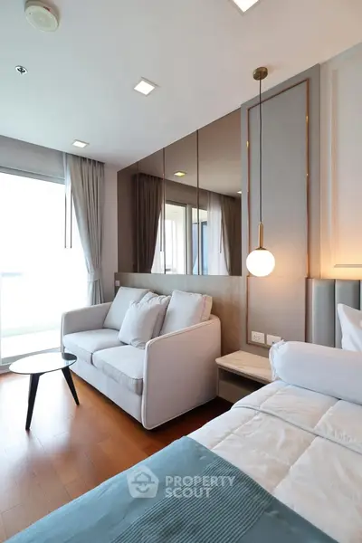 Modern bedroom with cozy sofa and stylish decor, featuring floor-to-ceiling windows for natural light.