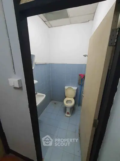 Compact bathroom with blue tiles and basic fixtures