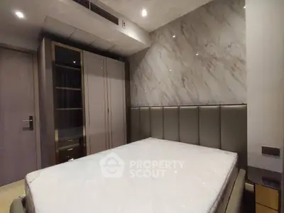 Modern bedroom with elegant marble accent wall and sleek wardrobe design.