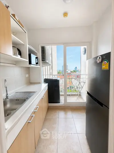 Modern kitchen with balcony view, featuring sleek cabinetry and stainless steel appliances.