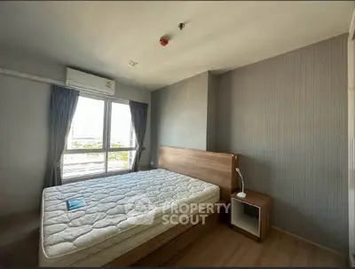 Spacious bedroom with large window and modern furnishings in a well-lit apartment.