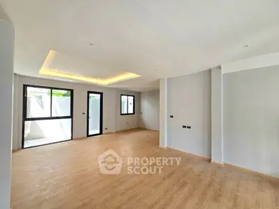 Spacious modern living room with wooden flooring and large windows for natural light.