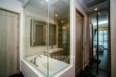 Modern bathroom with glass-enclosed bathtub and sleek fixtures in a stylish apartment.