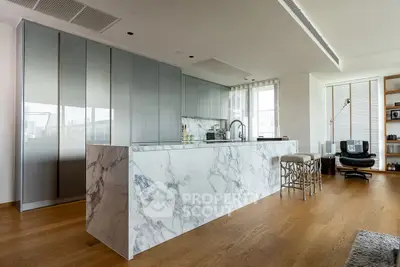 Luxurious modern kitchen with marble island and sleek cabinetry in open-plan living space.