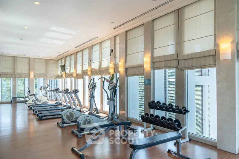 Luxurious gym with modern equipment and large windows in upscale residential building.