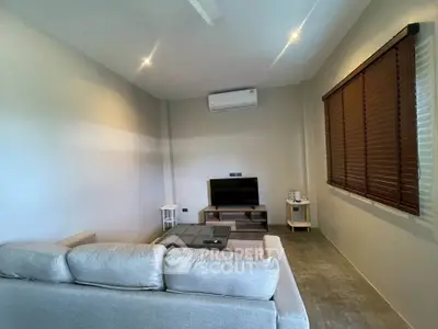 Modern living room with sleek design and neutral tones, featuring a cozy sofa and flat-screen TV.