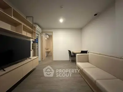 Modern living room with sleek furniture and open layout, featuring a large TV and cozy seating area.