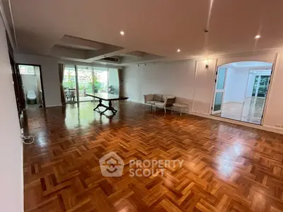 Spacious living room with elegant parquet flooring and large windows opening to a balcony.