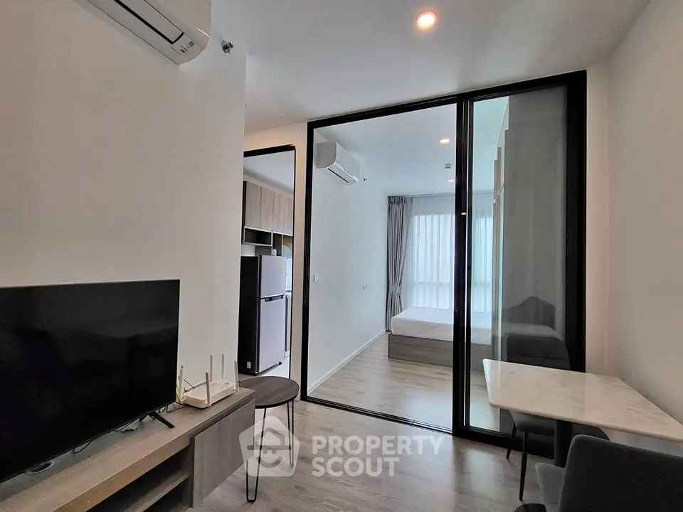 Modern apartment interior with open living area and bedroom, featuring sleek design and natural light.