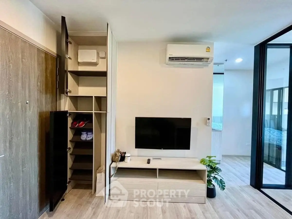 Modern living room with sleek storage and wall-mounted TV in stylish apartment.