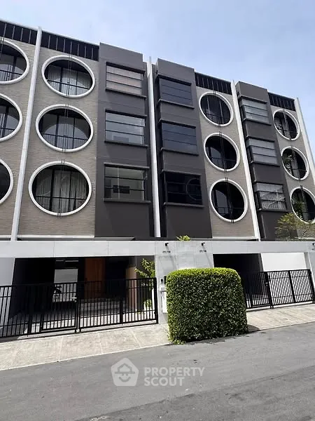 Modern apartment building with circular windows and sleek facade design.