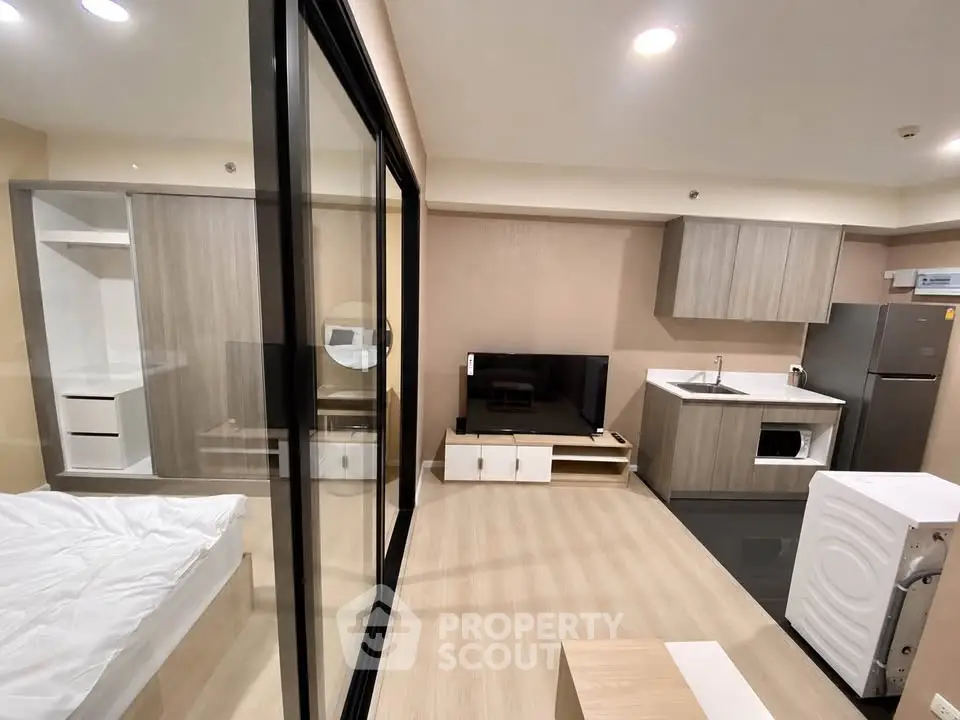 Modern studio apartment with open layout, featuring sleek kitchen and cozy living area.