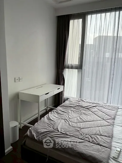 Cozy bedroom with modern furnishings and large window for natural light.