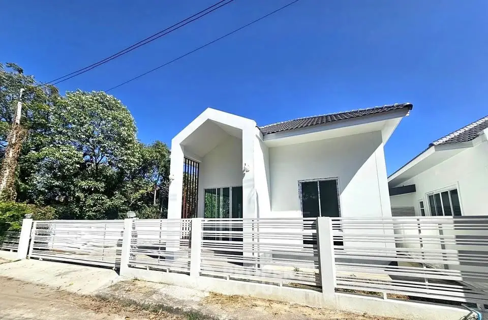 Modern white house exterior with sleek fence and clear blue sky.