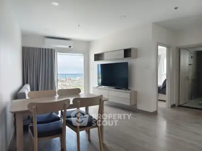 Modern living room with dining area and large TV, featuring a stunning city view.