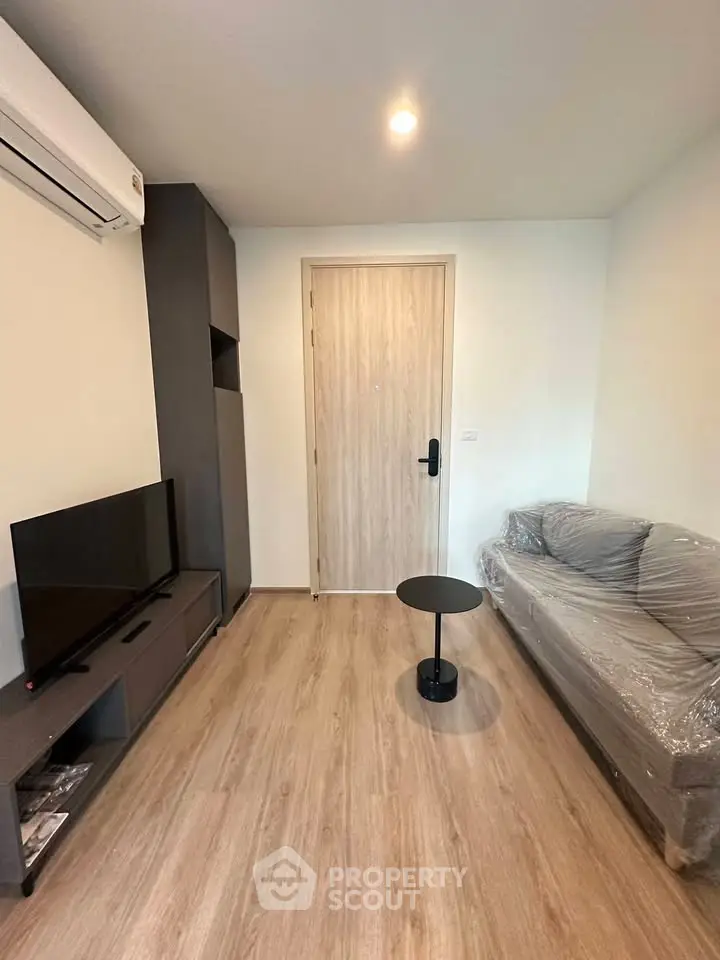 Modern living room with sleek furniture and wooden flooring, featuring a cozy sofa and flat-screen TV.