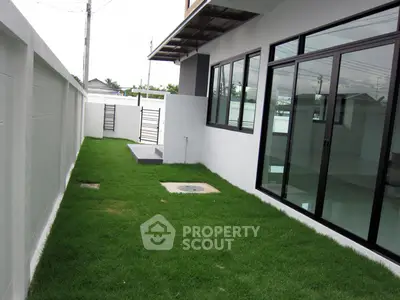 Modern house exterior with lush green lawn and large glass doors