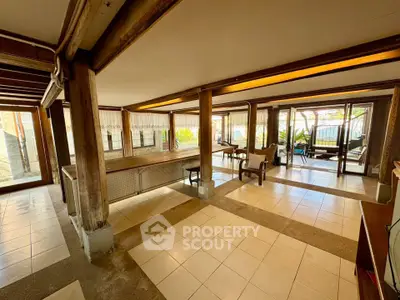 Spacious open-plan living area with large windows and wooden beams, perfect for entertaining.