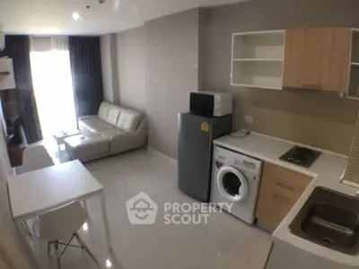 Modern open-layout living room with kitchen, featuring sleek appliances and cozy seating area.