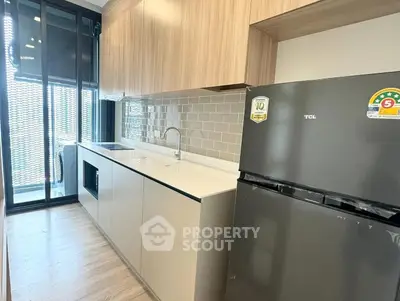 Modern kitchen with sleek cabinetry and stainless steel fridge in a stylish apartment.