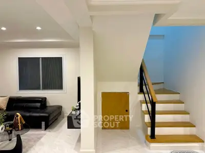 Modern living room with sleek staircase and stylish black leather sofa