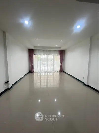 Spacious unfurnished living room with large windows and elegant curtains
