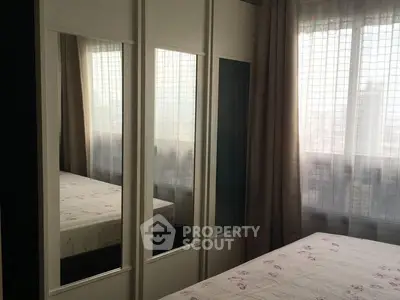 Cozy bedroom with mirrored wardrobe and large window for natural light.