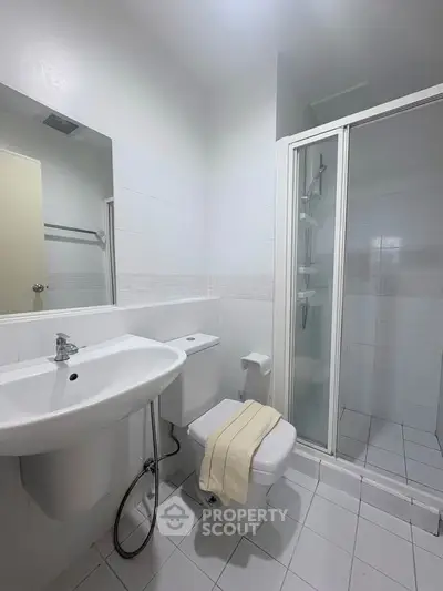 Modern bathroom with sleek white fixtures and a glass shower enclosure.
