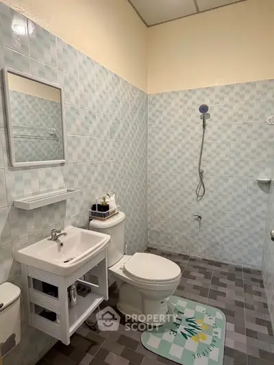 Modern bathroom with tiled walls, shower, and sink in a compact layout.