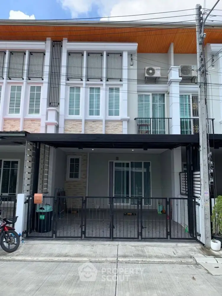 Modern townhouse exterior with gated parking and contemporary design.