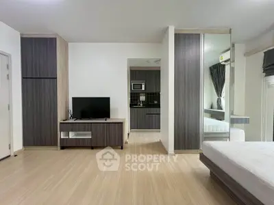 Modern studio apartment with sleek wooden flooring and compact kitchen area.