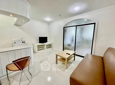 Modern living room with sleek furniture and minimalist design, featuring a TV and sliding glass doors.