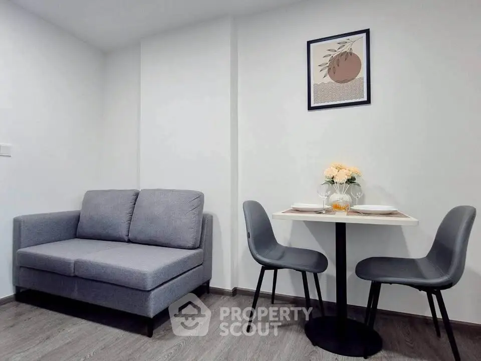Modern living room with cozy gray sofa and stylish dining area in a compact apartment.