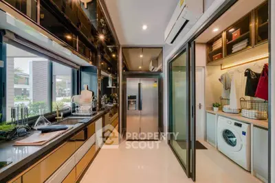 Modern kitchen with sleek appliances and laundry area, featuring open layout and stylish design.